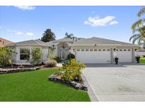 Beautiful home exterior with a well-manicured lawn, mature landscaping, and a spacious three-car garage at 1367 Honea Path, The Villages, FL 32162