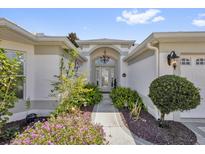 Inviting front entrance with beautiful landscaping and an elegant chandelier at 1367 Honea Path, The Villages, FL 32162