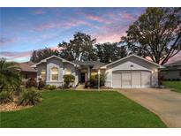 Charming one-story home featuring a well-manicured lawn and attached two-car garage at 21410 Royal St Georges Ln, Leesburg, FL 34748
