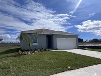 Charming single-story home featuring a two-car garage, manicured lawn, and beautiful landscaping at 2824 Supermarine Rd, Tavares, FL 32778