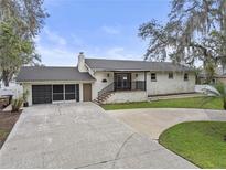 Charming single-story home with brick exterior, front porch, and a spacious driveway with attached garage at 31400 Saunders Dr, Tavares, FL 32778