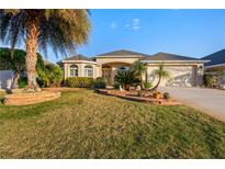 Charming single-story home featuring a lush lawn and well-manicured landscaping, complete with swaying palm trees at 3144 Mayflower Loop, The Villages, FL 32163