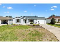Charming single-story home featuring a well-manicured front yard with a cozy seating area and a driveway leading to the garage at 3349 Ashbrook Pl, The Villages, FL 32162