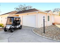Charming single-story home featuring a golf cart, a pristine two-car garage and a well-kept stone landscaped yard at 427 Cambio Ct, The Villages, FL 32159
