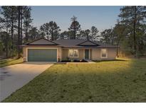 Charming single-story home featuring a lush front lawn and attached two-car garage, perfect for suburban living at 565 Malauka Radl, Ocklawaha, FL 32179