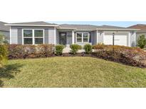 Charming single-story home with a well-manicured lawn and lush landscaping in front at 781 Nancy Dr, The Villages, FL 32163