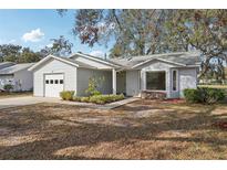 Charming single story home with light siding, attached garage, and manicured landscaping at 903 Dundee Cir, Leesburg, FL 34788