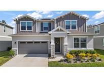 Charming two-story home with a well-manicured lawn and gray exterior with stone trim accents and a two car garage at 10177 Spring Lake Dr, Clermont, FL 34711