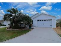 Charming single-story home featuring a two-car garage, a well-manicured lawn, and tropical landscaping at 1808 Endsley Ct, The Villages, FL 32162