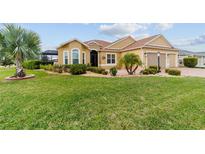 Charming single-story home with a lush lawn, colorful landscaping, and a welcoming entrance at 2050 Biller Cir, The Villages, FL 32163