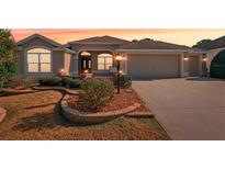 Charming one-story home featuring a neutral color palette, arched windows, and well-manicured landscaping at 2311 Bramble Ter, The Villages, FL 32162