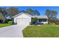 Charming single-story home boasts a well-manicured lawn and attached two-car garage at 26315 Newcombe Cir, Leesburg, FL 34748