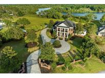 Stunning aerial view of a luxury home featuring a circular driveway, manicured lawn, and mature trees near a picturesque lake at 27852 Lake Jem Rd, Mount Dora, FL 32757