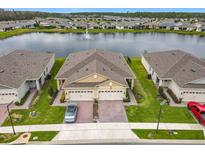 Stunning aerial view of home showcasing a beautiful lake, fountain, and lush landscaping at 3449 Meadow Beauty Way, Clermont, FL 34714