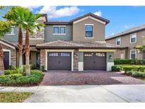 Charming townhome featuring a well-kept brick driveway, two-car garage, and lush landscaping at 9040 Azalea Sands Ln, Davenport, FL 33896