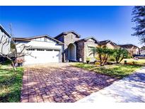 Charming single-Gathering home featuring a brick driveway, stone accents, and a two-car garage at 9188 Chandler Dr, Groveland, FL 34736