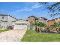 Beautiful single-story home featuring stone accents, a two-car garage, and a well-manicured front yard at 9188 Chandler Dr, Groveland, FL 34736