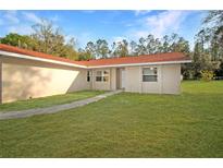 Single story home showcasing a lush lawn and a traditional facade with a clean pathway to the entrance at 11740 E Highway 25, Ocklawaha, FL 32179