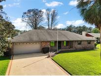 Single story brick home with an attached garage, well maintained lawn, and mature landscaping at 12320 Blue Heron Way, Leesburg, FL 34788