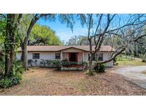 Charming single-story home featuring a cozy front porch and mature trees at 1236 Selman Rd, Leesburg, FL 34748