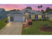 Charming single-story home with well-manicured lawn, two-car garage, and beautiful landscaping at 1256 Camero Dr, The Villages, FL 32159