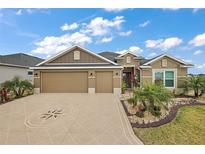 Charming home featuring a well-manicured lawn, a three-car garage, and beautiful landscaping on a sunny day at 1603 Mcmurtrie Loop, The Villages, FL 34762