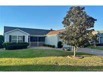 Charming single-story home with a well-maintained lawn, mature tree, and screened-in porch, perfect for outdoor living at 2427 Tamarind Grove Run, The Villages, FL 32162