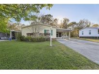 Charming single-story home with a well-maintained lawn, covered carport and lush trees at 2557 Karen Dr, Mount Dora, FL 32757