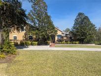 Charming tan home featuring a manicured front yard and inviting entryway on a sunny day at 42316 E Saffron Ct, Eustis, FL 32736