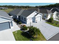 Beautiful single-story home featuring an attractive driveway with a decorative design and manicured landscaping at 511 Van Deen Pl, The Villages, FL 34762