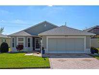 Charming single-story home featuring a brick driveway, two-car garage, manicured lawn, and meticulous landscaping at 5718 Illumination Ln, Leesburg, FL 34748