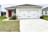 Charming single-story home with a well-maintained lawn, white garage door, and bright red front door at 726 Eagle Landing Blvd, Winter Haven, FL 33880