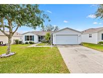 Charming single-story home featuring a well-manicured lawn and a two-car garage at 8425 Se 177Th Bartram Loop, The Villages, FL 32162