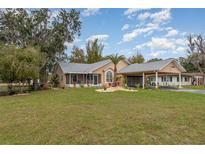 Charming home with well-manicured lawn, covered carport, and screened porch, offering inviting curb appeal at 11415 Palmetto Dr, Tavares, FL 32778