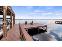Scenic view of a boat dock with chairs, a lift, and beautiful water views, ideal for lakeside relaxation at 12117 Cypress Ln, Clermont, FL 34711