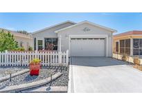 Charming home exterior features a white picket fence, manicured landscaping, and a well-maintained driveway at 2058 Thornton Ter, The Villages, FL 32162