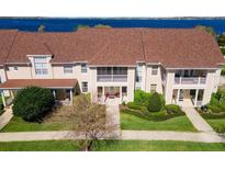 Inviting townhome exterior features a covered porch, balcony, manicured lawn, and lush landscaping near the water at 220 Nautica Mile Dr, Clermont, FL 34711