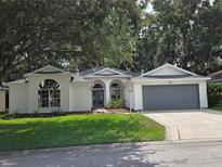 Charming one-story home with a well-manicured lawn, a gray garage door, and lush trees at 3733 Plantation Blvd, Leesburg, FL 34748
