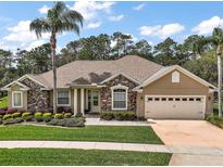 Charming home featuring stone accents, a well-manicured lawn, and a two-car garage at 5029 Greenbriar Trl, Mount Dora, FL 32757