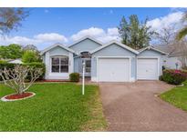 Charming light blue single-story home featuring a two-car garage and well-maintained landscaping at 509 Ventura Ct, The Villages, FL 32159