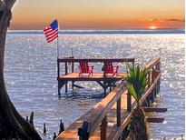 Waterfront dock with two Adirondack chairs faces west for a beautiful sunset over the water at 11215 Dead River Rd, Tavares, FL 32778