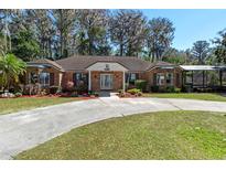 Charming brick home with well-manicured landscaping and a circular driveway at 11215 Dead River Rd, Tavares, FL 32778