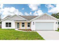 Charming single-story home with a well-manicured lawn, two-car garage, and a welcoming light-green front door at 13334 Sw 107 St, Dunnellon, FL 34432