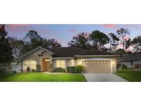 Charming single-story home with a well-manicured lawn and a two-car garage at dusk at 13753 Via Roma Cir, Clermont, FL 34711