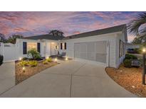 Charming single-story home featuring a well-manicured yard, a two-car garage, and a warm, inviting entrance at 16800 Se 80Th Bathurst Ct, The Villages, FL 32162