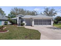 Charming single-story home with well-manicured lawn, attached two-car garage, and screened porch at 20740 Queen Alexandra Dr, Leesburg, FL 34748