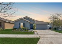 Charming single-story home with a well-manicured lawn, gray siding, and a two-car garage, perfect for a small Gathering at 212 Taft Dr, Davenport, FL 33837