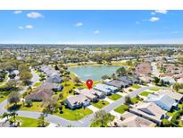 Beautiful aerial view of a house in a community with a pond and lush greenery under a bright, sunny sky at 2310 Ambler Cir, The Villages, FL 32162