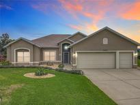 Charming home featuring a well-manicured lawn, tasteful landscaping, and a three-car garage at 24002 Robinwood St, Leesburg, FL 34748