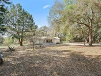 Expansive front yard featuring a charming single-story home with a covered porch and mature trees at 37820 Ridgecrest Ln, Lady Lake, FL 32159